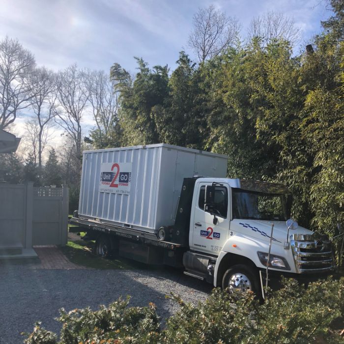 a Unit2Go portable storage unit on a delivery vehicle being unloaded into a residential yard