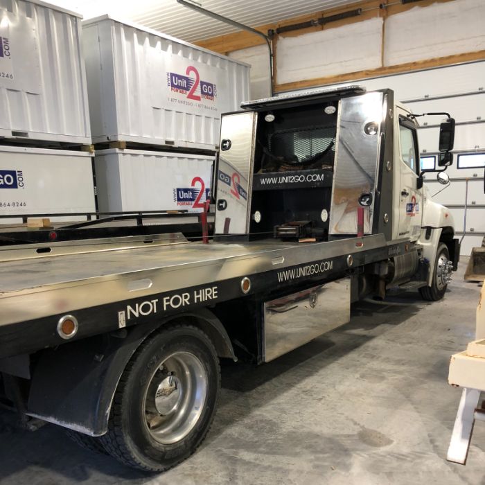 A Unit2Go portable container delivery vehicle parked in a warehouse next to portable storage containers